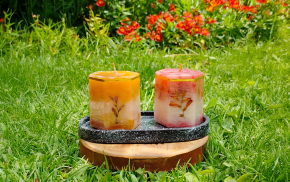 Par de velas exagonales con flores secas incrustadas sobre base de madera