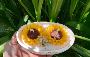 Dos velas decoradas con flores de girasol en recipiente circular