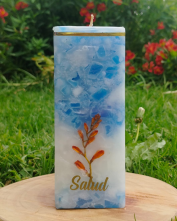 Vela cuadrada azul con el grabado “Salud” y diseño botánico
